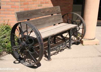 A June picture of a Wagon Wheel Bench in the of the Forsyth City Hall Image is from the Forsyth Montana Picture Tour.